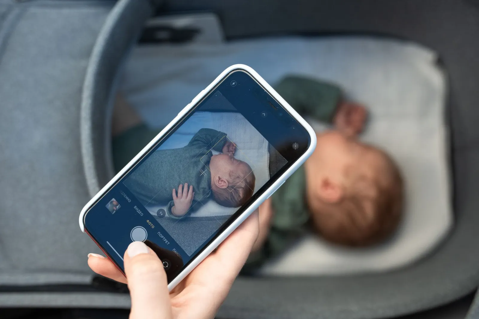 A smartphone capturing a peaceful newborn baby sleeping in a crib, highlighting modern parenthood.